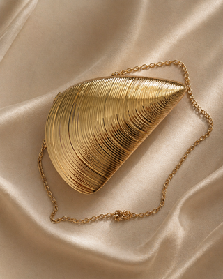 Gold clutch bag with chain on a beige fabric background
