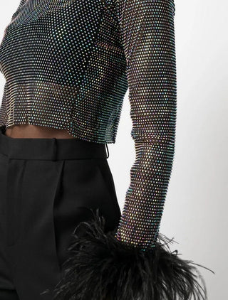 Studded long-sleeve top with feathered bottom on a plain background