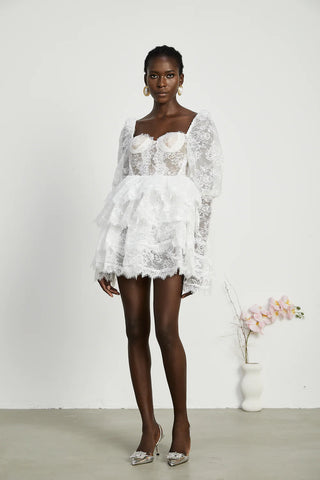 Elegant white mini dress with long puff sleeves, square neck, lace trim, bustier style, ruffled details, and flounce hem, perfect for cocktail parties and bridal events.