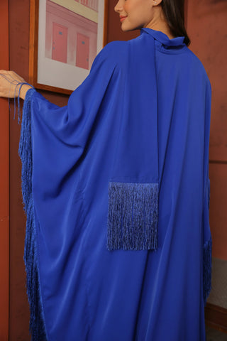 Person wearing a blue garment with tassels indoors