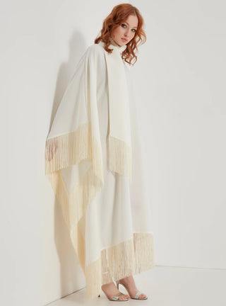 Woman wearing a long, light-colored scarf with fringe details on a white background