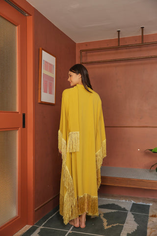 Woman in a yellow dress standing in a room with a red wall and framed picture.