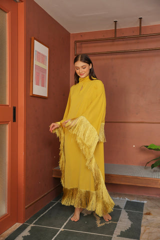 Woman in a yellow dress standing in a room with a red wall and framed picture.