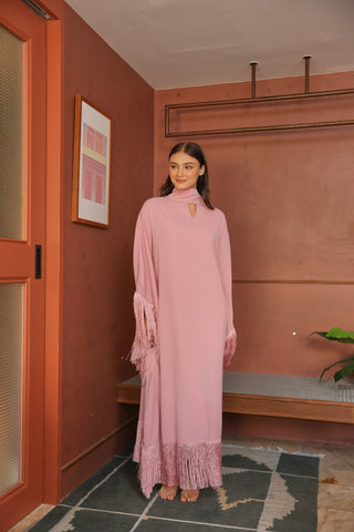 Woman in a pink dress standing in a room with a red wall and a plant.
