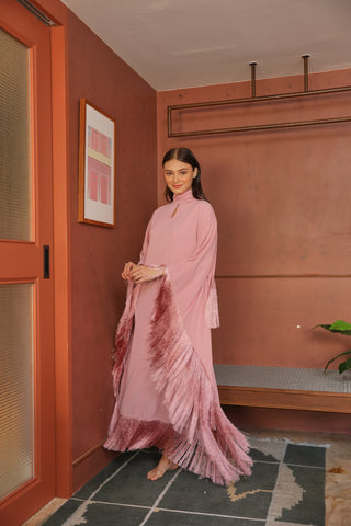 Woman in a pink dress standing in a room with a red wall and framed picture.