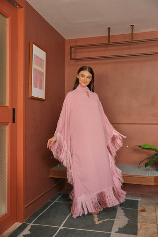 Woman in a pink dress standing in a room with a red wall and a plant.
