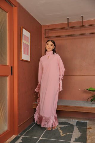 Woman in a pink dress standing in a room with a red wall and a plant.