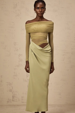 Woman wearing a green off-shoulder dress against a beige background