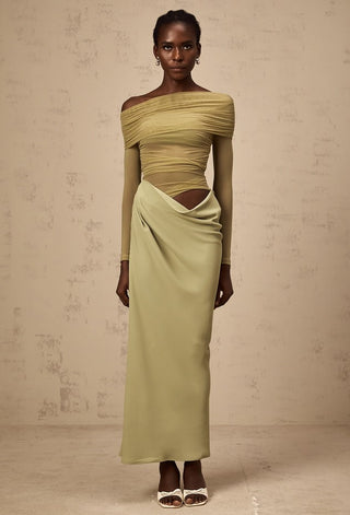 Woman wearing a green off-shoulder dress against a beige background