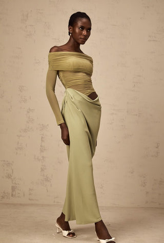 Model wearing a green off-shoulder top and skirt against a beige background