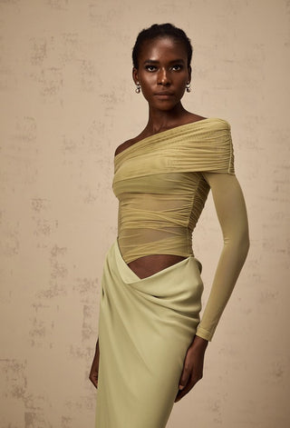 Woman wearing a light green off-shoulder dress against a beige background
