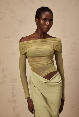 Woman wearing a light green off-shoulder dress against a beige background