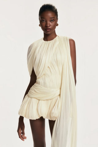 Woman wearing a flowing white dress against a plain background