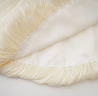 Close-up of cream-colored fabric with a subtle pattern on a light background