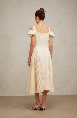 Woman wearing a neutral pleated midi dress with flutter sleeves and darted bodice, ideal for elegant summer events, wedding guest looks, or garden parties.