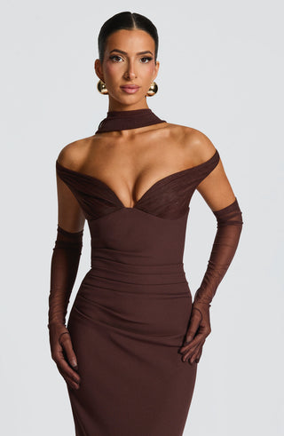 Woman wearing a brown off-shoulder dress with sheer sleeves on a white background