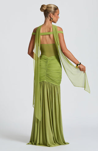 Woman wearing a green evening gown with a sheer overlay on a white background