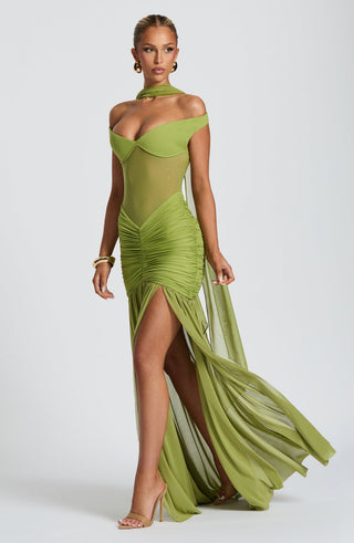 Woman wearing a green evening gown with a high slit on a white background