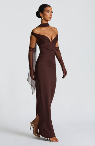 Woman wearing a brown evening gown with sheer sleeves on a white background