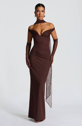 Woman wearing a brown evening gown with sheer sleeves on a white background