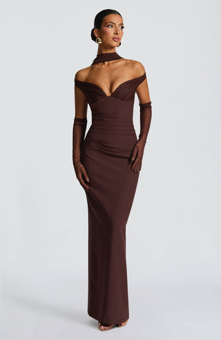 Woman wearing a brown evening gown with long gloves on a white background