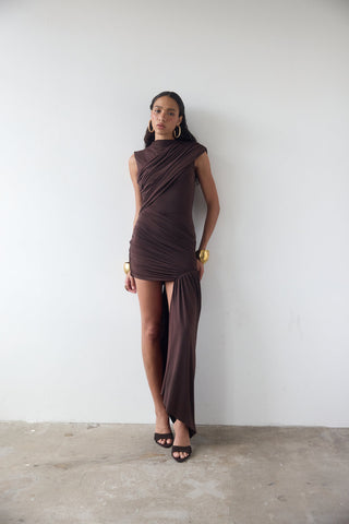 Woman wearing a brown dress against a white wall
