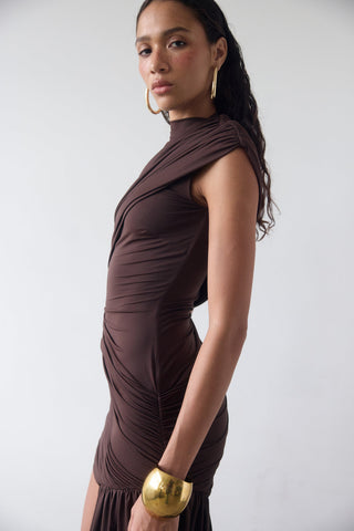 Woman wearing a brown dress with gold accessories on a white background