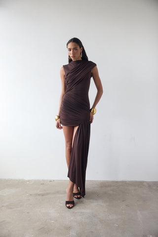 Woman wearing a brown dress against a white wall