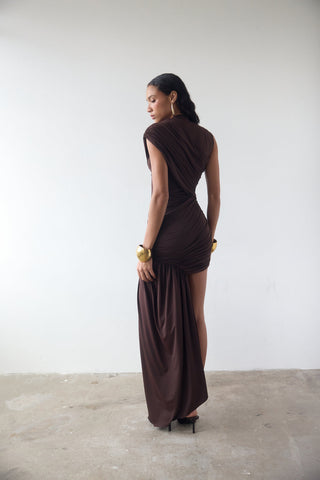 Woman wearing a brown evening gown against a white wall