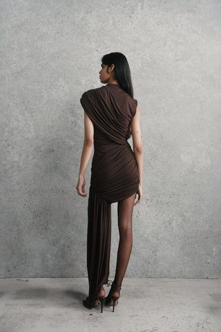 Woman wearing a brown dress against a gray concrete wall