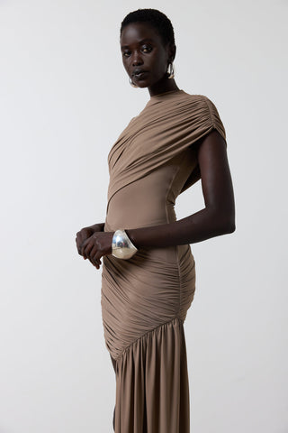 Woman wearing a brown draped dress against a white background