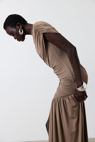 Woman wearing a long, flowing brown dress against a white background