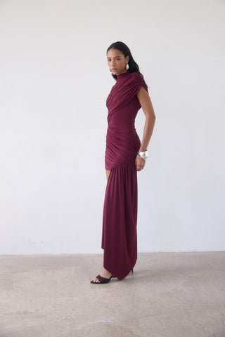 Woman wearing a burgundy evening gown against a white background