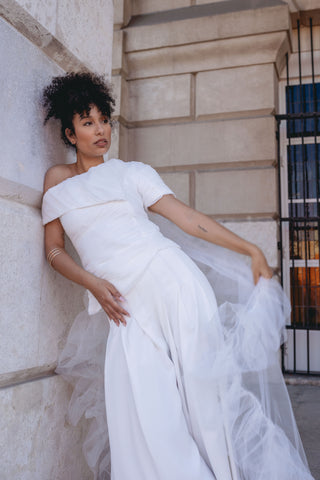 White pant suit set bridal - Asymmetric off-shoulder top with entire gathering detail and fitted waist, paired with wide-leg pleated pants. Perfect for modern brides, business attire, and summer events. Elegant and sophisticated design ideal for versatile occasions.