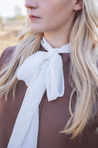 Brown mini dress with shoulder pads, designed for business wear. A chic fall/autumn designer dress featuring long sleeves and a tulle bow scarf, perfect for a professional and stylish look.