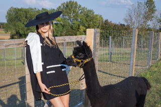 Model wearing a black and white beaded knit cape from the Desole Collection AW24 by Cielie, featuring a detachable satin bow and semi-fitted silhouette. This elegant monochrome cape coat is perfect for formal events or casual chic outfits, designed for cooler weather.