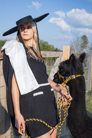 Model wearing a black and white beaded knit cape from the Desole Collection AW24 by Cielie, featuring a detachable satin bow and semi-fitted silhouette. This elegant monochrome cape coat is perfect for formal events or casual chic outfits, designed for cooler weather.