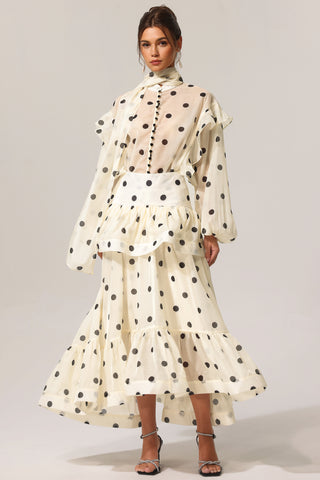 Woman wearing a polka dot dress with long sleeves on a plain background