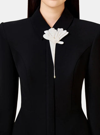 Model wearing long-sleeve black business dress with white flower detailing and contrasting white sleeve ends. This elegant and versatile formal dress is perfect for professional settings and autumn/fall business attire, combining modern style with sophistication for businesswomen.