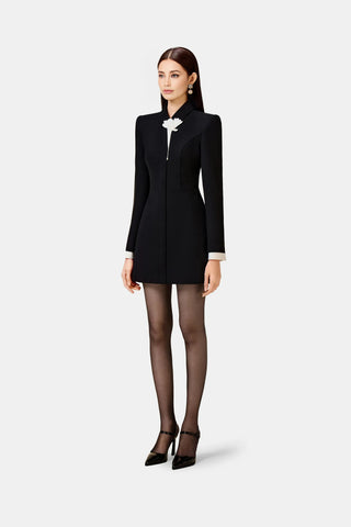 Model wearing the Shane long-sleeve black business dress with white flower detailing and contrasting white sleeve ends. This elegant and versatile formal dress is perfect for professional settings and autumn/fall business attire, combining modern style with sophistication for businesswomen.