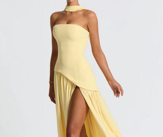 Model wearing Soleil Siren Maxi Dress in buttercream yellow, strapless with asymmetrical crepe bodice and flowing chiffon skirt with thigh-high slit.