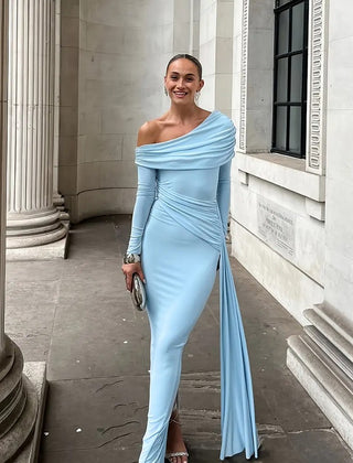 Woman in a light blue off-shoulder dress standing in front of classical architecture.