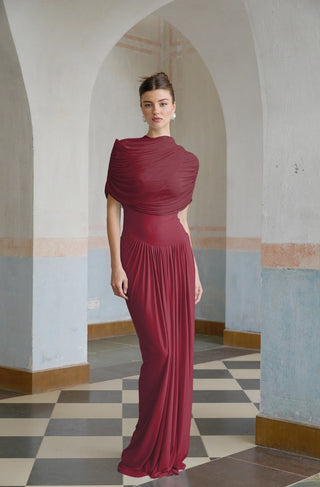 Woman in a burgundy dress standing in an arched hallway with checkered floor.