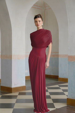 Woman in a burgundy evening gown standing in an arched hallway with checkered floor.