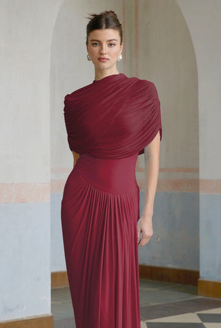 Woman wearing a burgundy dress in an indoor setting with arched doorways.